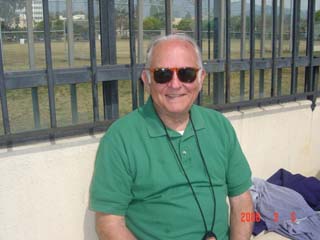 Kenny, in sunglasses, smiling on pooldeck